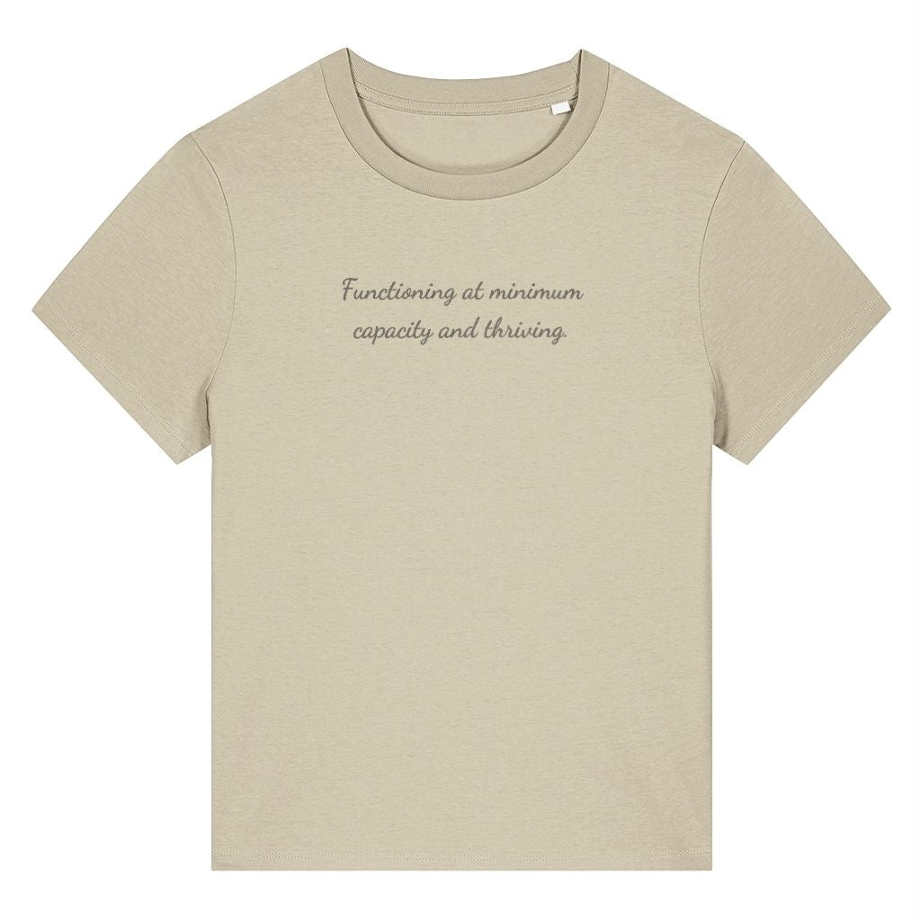 Beige organic cotton women's t-shirt featuring the funny quote ‘Functioning At Minimum Capacity And Thriving.’ by Rivaex Clothing