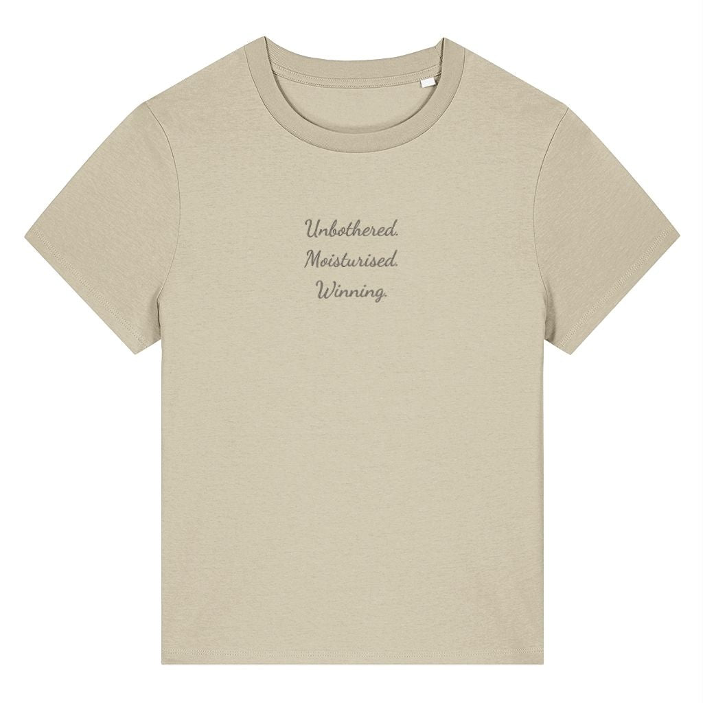 Beige organic cotton women's t-shirt featuring the confidence quote ‘Unbothered. Moisturised. Winning.’ by Rivaex Clothing