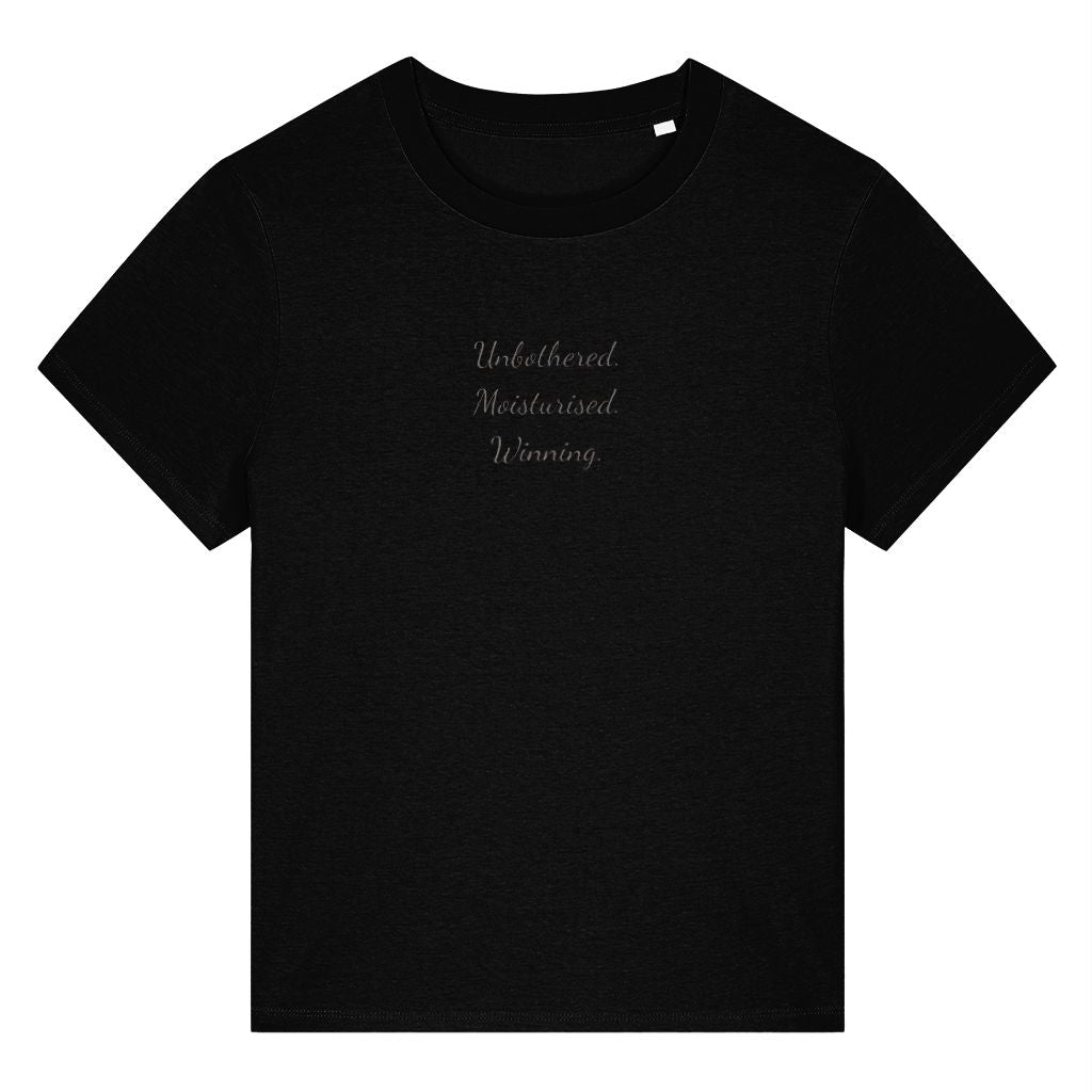 Black organic cotton women's t-shirt featuring the confidence quote ‘Unbothered. Moisturised. Winning.’ by Rivaex Clothing