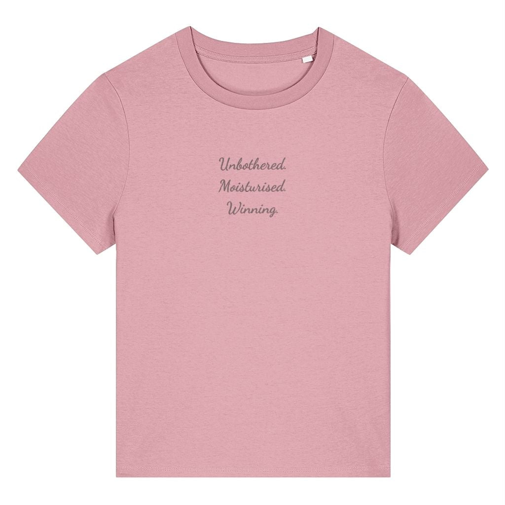 Pink organic cotton women's t-shirt featuring the confidence quote ‘Unbothered. Moisturised. Winning.’ by Rivaex Clothing